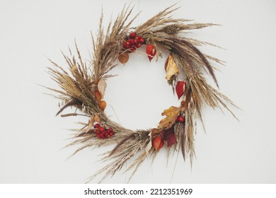 Stylish Autumn Wreath Hanging On White Wall Outdoor. Fall Decor And Arrangement Of Farmhouse. Thanksgiving. Rustic Autumn Wreath With Dried Grass, Berries, Herbs And Leaves