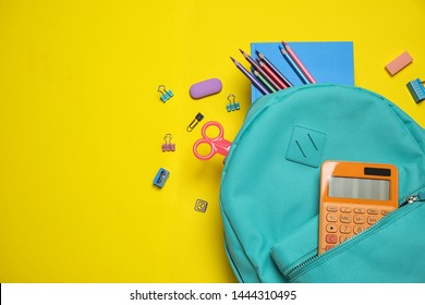 Stylish backpack with different school stationary on yellow background, top view. 