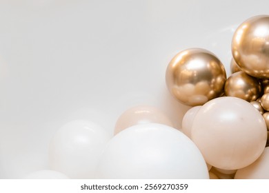 Stylish balloon composition with white, blush pink and metallic gold balloons arranged at the bottom of a light grey backdrop. Clean, minimalist corner setup perfect for celebrations.