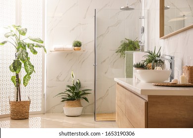 Stylish bathroom interior with countertop, shower stall and houseplants. Design idea - Shutterstock ID 1653190306