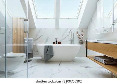 Stylish bathroom interior design with marble panels. Bathtub, towels and other personal bathroom accessories. Modern glamour interior concept. Roof window. Template. - Shutterstock ID 2109735392