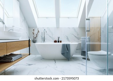 Stylish bathroom interior design with marble panels. Bathtub, towels and other personal bathroom accessories. Modern glamour interior concept. Roof window. Template. - Shutterstock ID 2173595073