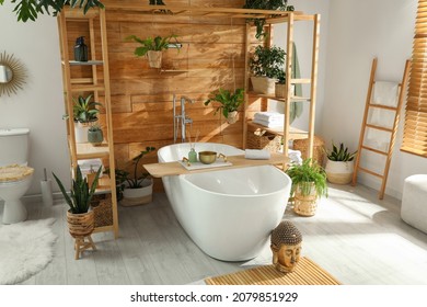 Stylish bathroom interior with white tub and green houseplants near wooden wall. Idea for design