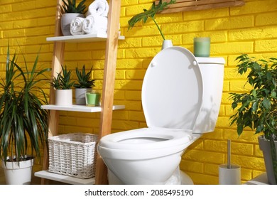 Stylish Bathroom With Toilet Bowl And Green Plants Near Yellow Brick Wall. Interior Design