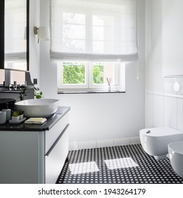 Stylish Bathroom With Toilet, Mosaic Black And White Floor, Window And Fancy Washbasin With Mirror And Chest Of Drawers