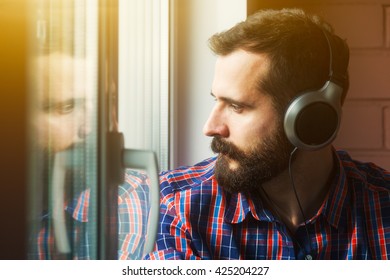 stylish bearded man  in headphones listening to music near window with reflection - Shutterstock ID 425204227