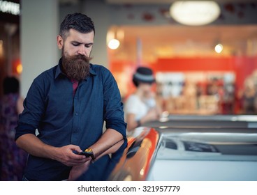 Stylish Bearded Man With The Phone In The Hands Of A Shopping Center On The Background Of Shop Windows