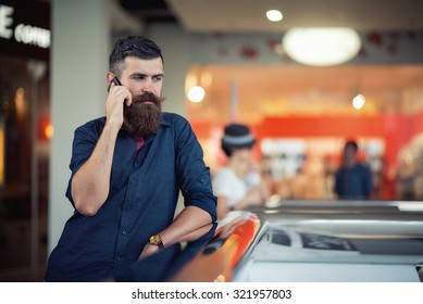 Stylish Bearded Man With The Phone In The Hands Of A Shopping Center On The Background Of Shop Windows