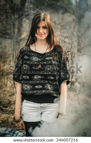 stylish beautiful  brunette girl in ethnic clothes in the amazing woods with fire