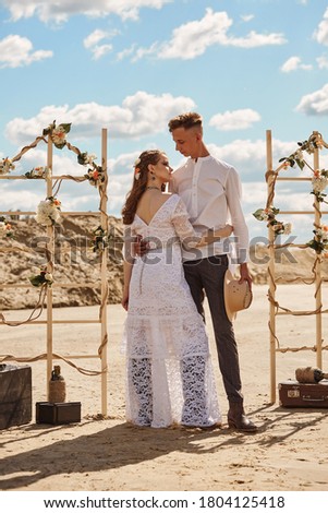 Stylish beautiful couple on a summer sandy beach, the concept of the wedding in style Boho