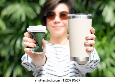 A stylish beautiful woman holding takeaway coffee cup in both hands, one is a single use paper cup with plastic lid the other one is a reusable stainless tumbler. Say no to plastic, No straw, 0 waste 
