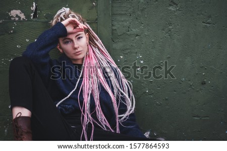 Stylish beautiful young blonde girl with pink dreadlocks in a coat, beauty and fashion concept, trends of millennials and hipsters,