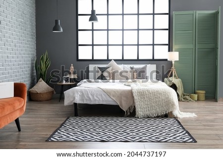 Stylish bedroom with comfortable bed and folding screen