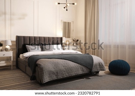 Stylish bedroom interior with large comfortable bed and chest of drawers