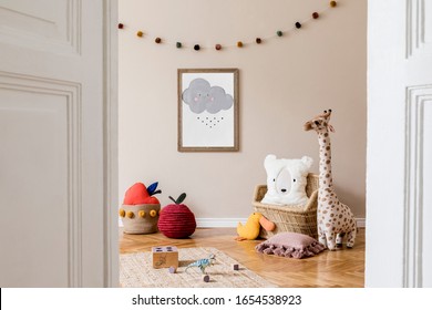 Stylish and beige scandinavian decor of kid room with mock up poster frame, design furnitures, natural toys, hanging colorful cotton balls, teddy bears, plush animal and child accessories. Template