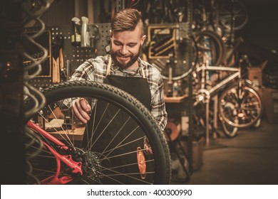 Stylish bicycle mechanic doing his professional work in workshop.