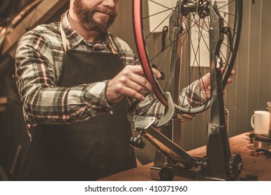 Stylish bicycle mechanic doing his professional work in workshop.