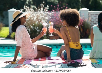 Stylish Biracial Young Females Toasting Cocktails While Having Fun Pool Party During Summer. Hangout, Drink, Unaltered, Friendship, Togetherness, Social Gathering, Enjoyment And Weekend Activities.