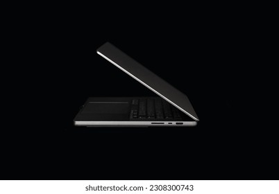 Stylish black background for a website with a laptop on a dark background. Minimalistic photo in high quality with an open laptop. M1 pro website. Side view.  