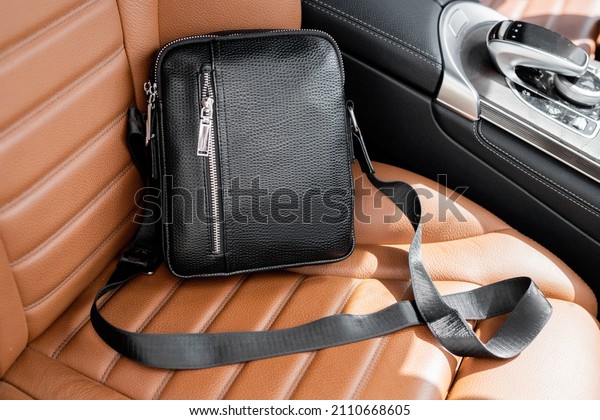 Stylish\
black business men\'s leather bag on the passenger seat next to the\
driver in premium cars with a modern\
interior.