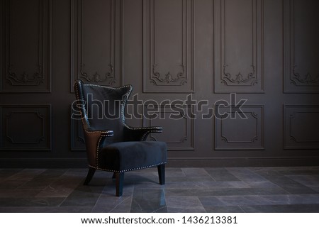 Stylish black chair against a dark gray wall. Stylish chair on wall background, copy space, fashionable interior
