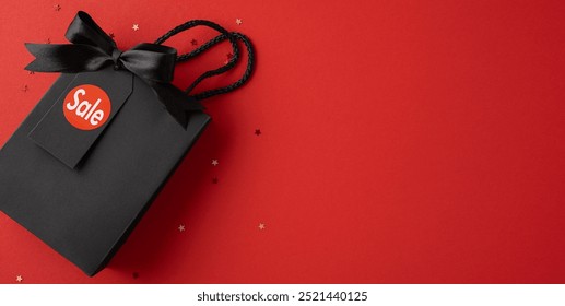 A stylish black gift bag adorned with a sale tag on a vibrant red background, symbolizing Black Friday and holiday shopping excitement - Powered by Shutterstock