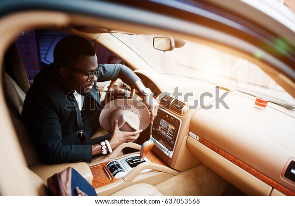Stylish black man sitting behind
the wheel of luxury car. Rich african american
businessman.