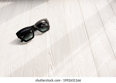 Stylish Black Sunglasses. Summer Background Mockup Template Text. Pattern Top View Above White Wooden Background. Fashion Accessories For Beach. Women Summer Design Sunglasses Vacation Concept