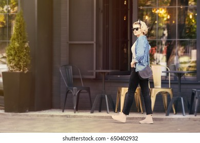 A stylish blonde is walking down the street. The sun - Powered by Shutterstock