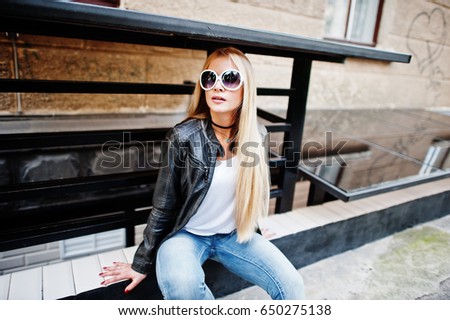 Stylish blonde woman wear at jeans, suglasses, choker and leather jacket at street. Fashion urban model portrait.