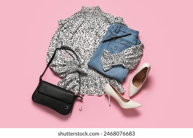 Stylish blouse with jeans, bag, high heels and accessories on pink background