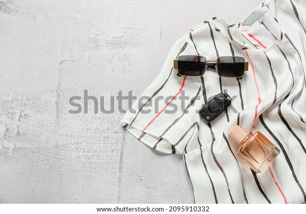 Stylish blouse, sunglasses, car key and bottle\
of perfume on light\
background