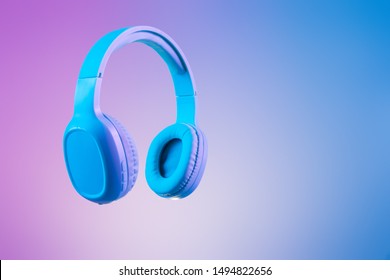 Stylish blue headphones on multi coloured / duo tone background lighting - lifestyle and fashion object concept image.