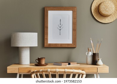 Stylish Bohemian Interior Of Home Office Space With Wooden Desk, Rattan Armchair, Brown Mock Up Poster Frame, Hat, Office Supplies, Lamp, Decoration And Elegant Personal Accessories In Home Decor.