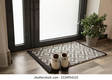 Stylish boots on door mat in hall
