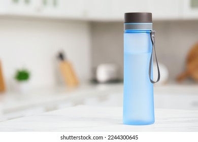 Stylish bottle of water on table in kitchen. Space for text