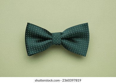 Stylish bow tie with polka dot pattern on pale green background, top view