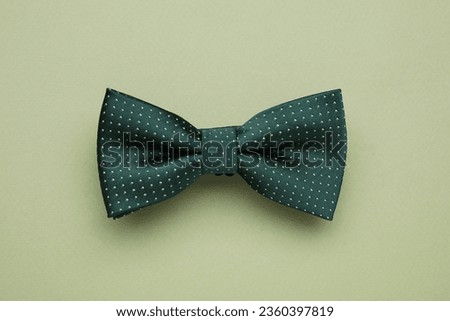 Stylish bow tie with polka dot pattern on pale green background, top view