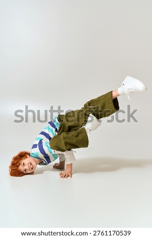 Stylish boy confidently performs a breakdancing move, displaying joy and creativity in action.