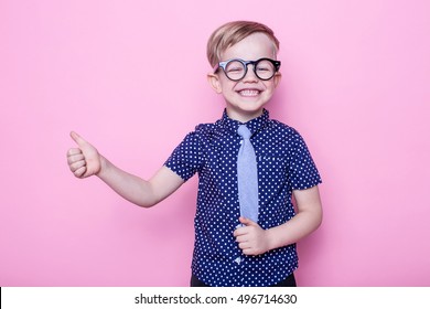 Stylish Boy In Shirt And Glasses With Big Smile. Ok. School. Preschool. Fashion. Studio Portrait Over Pink Background