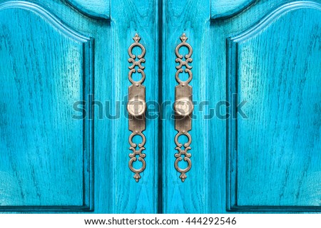 Stylish brass door handles on a hardwood cabinet or closet with ornate escutcheons and raised panels on the doors in a close up frontal view conceptual of furnishing and interior decor