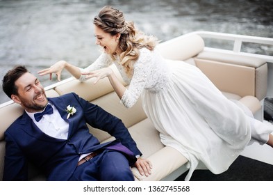 Stylish Bride And Groom On Their Wedding Day, Having Fun And Smiling On A Boat Trip On The River