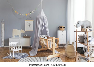 Stylish And Bright Scandinavian Decor Of  Newborn Baby Room With Mock Up Poster, White Design Furnitures, Natural Toys, Hanging Grey Canopy With Wooden Cradle, Bookstand, Accessories And Teddy Bears. 