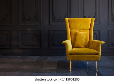Stylish bright yellow chair against a dark gray wall. Stylish chair on wall background, copy space, fashionable interior