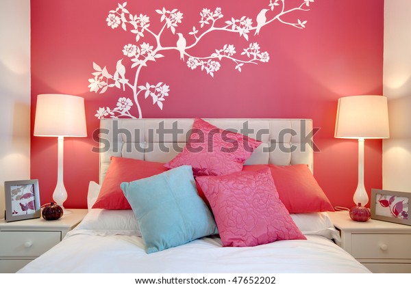 Stylish brightly decorated modern bedroom with wall mural and cushions