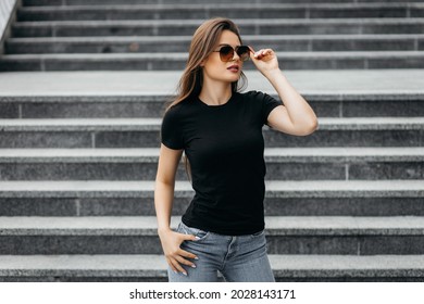 Stylish Brunette Girl Wearing Black T-shirt And Glasses Posing Against Street , Urban Clothing Style. Street Photography