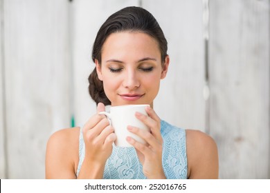 Stylish brunette holding a mug against bleached wooden fence