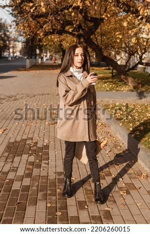 A stylish brunette woman walks around the autumn city. The season is autumn.