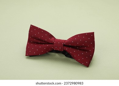 Stylish burgundy bow tie with polka dot pattern on pale green background - Powered by Shutterstock