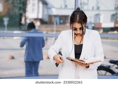 Stylish Businesswoman Reviewing Notes in a Modern Urban Setting. - Powered by Shutterstock